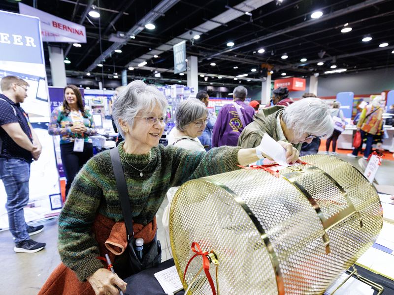 Visitors browsing stands along a busy exhibit hall aisle