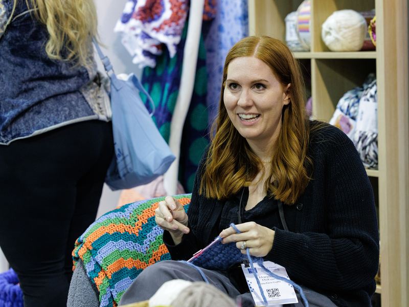 A visitor browsing shelves of yarn at a festival stand